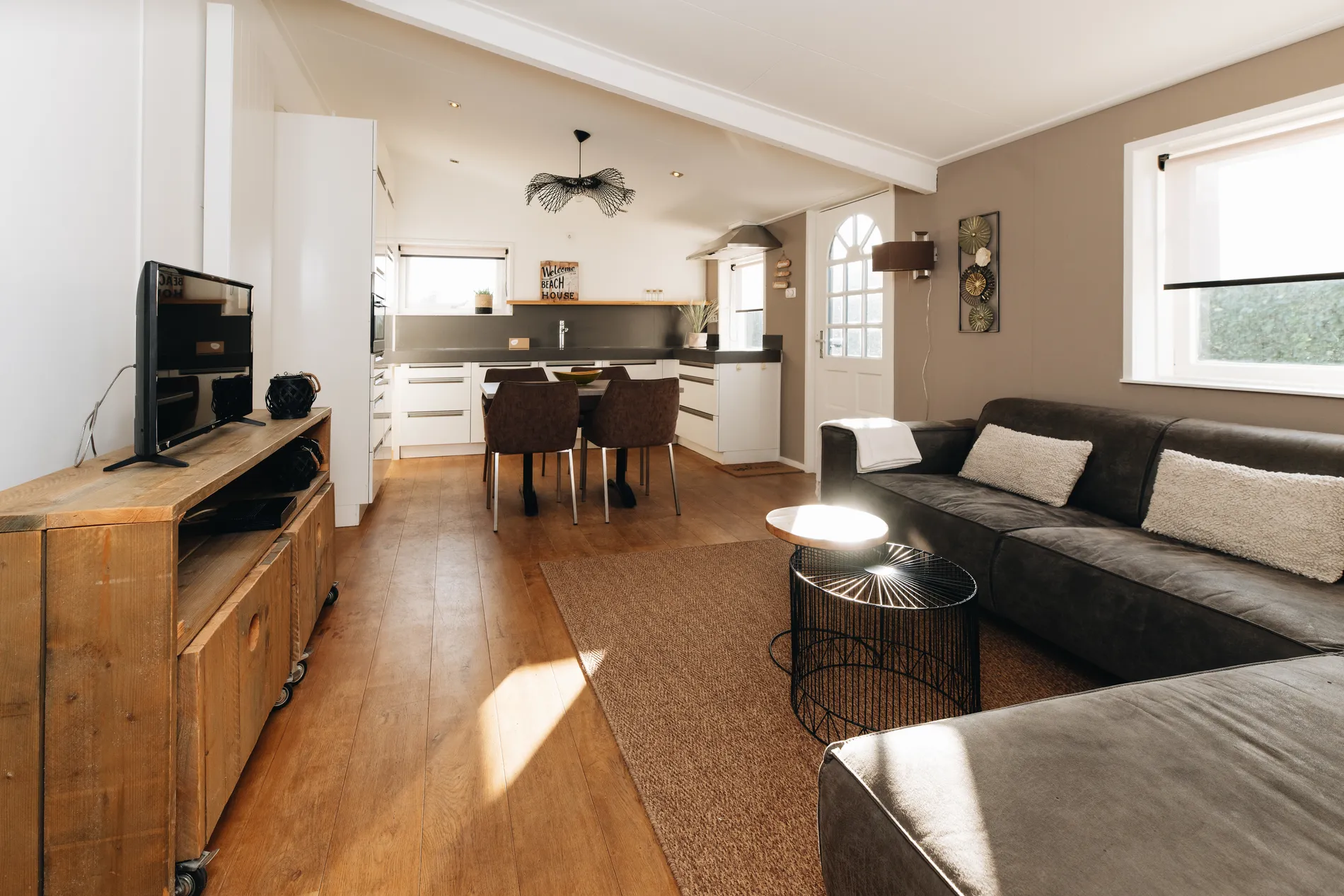 Overzicht van de lichte, open woonruimte met verbinding tussen de moderne keuken en de zithoek.